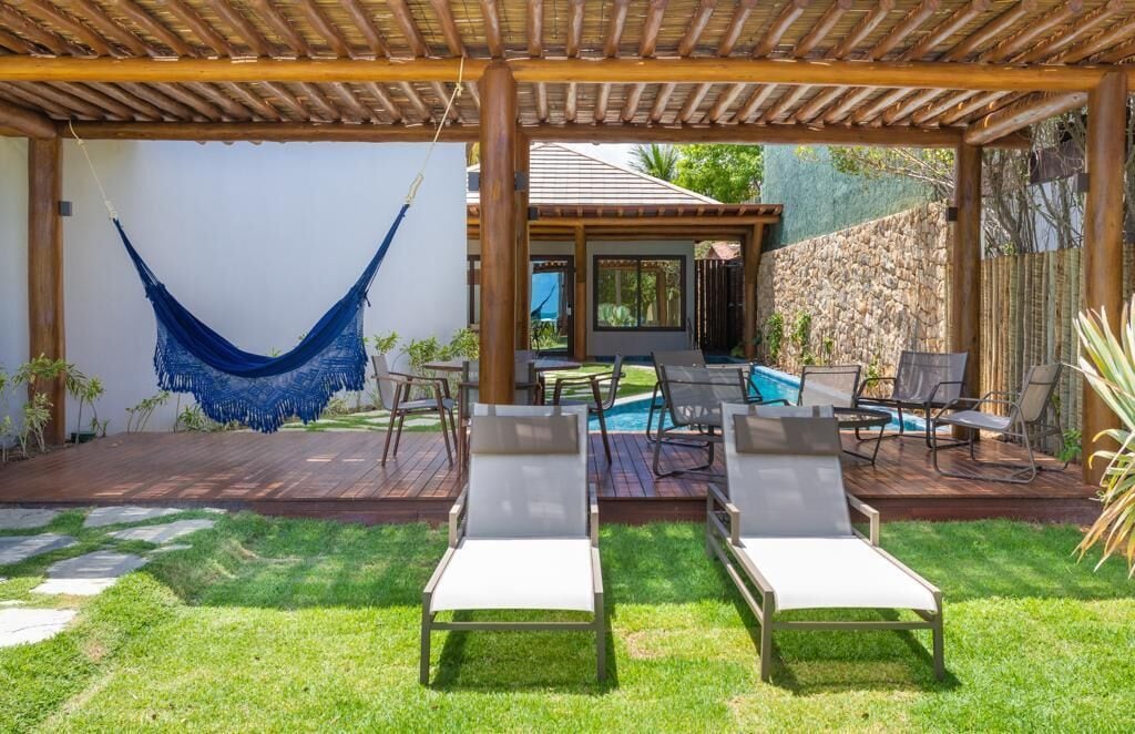 Un patio cubierto con una hamaca, sillones de descanso y una zona de piscina.