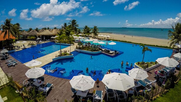 A resort pool area with multiple swimming pools, lounge chairs, and umbrellas. - Serrambi Resort (Ipojuca)