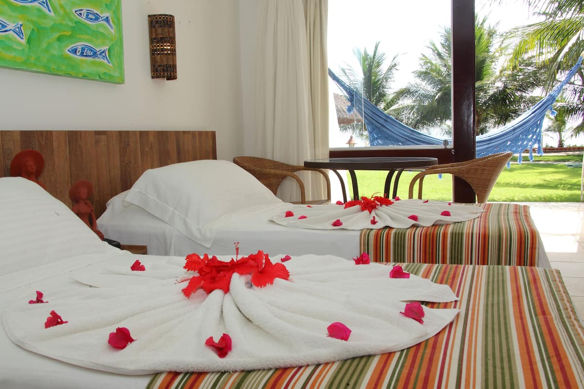 A hotel room with two beds, a hammock, and a view of palm trees.