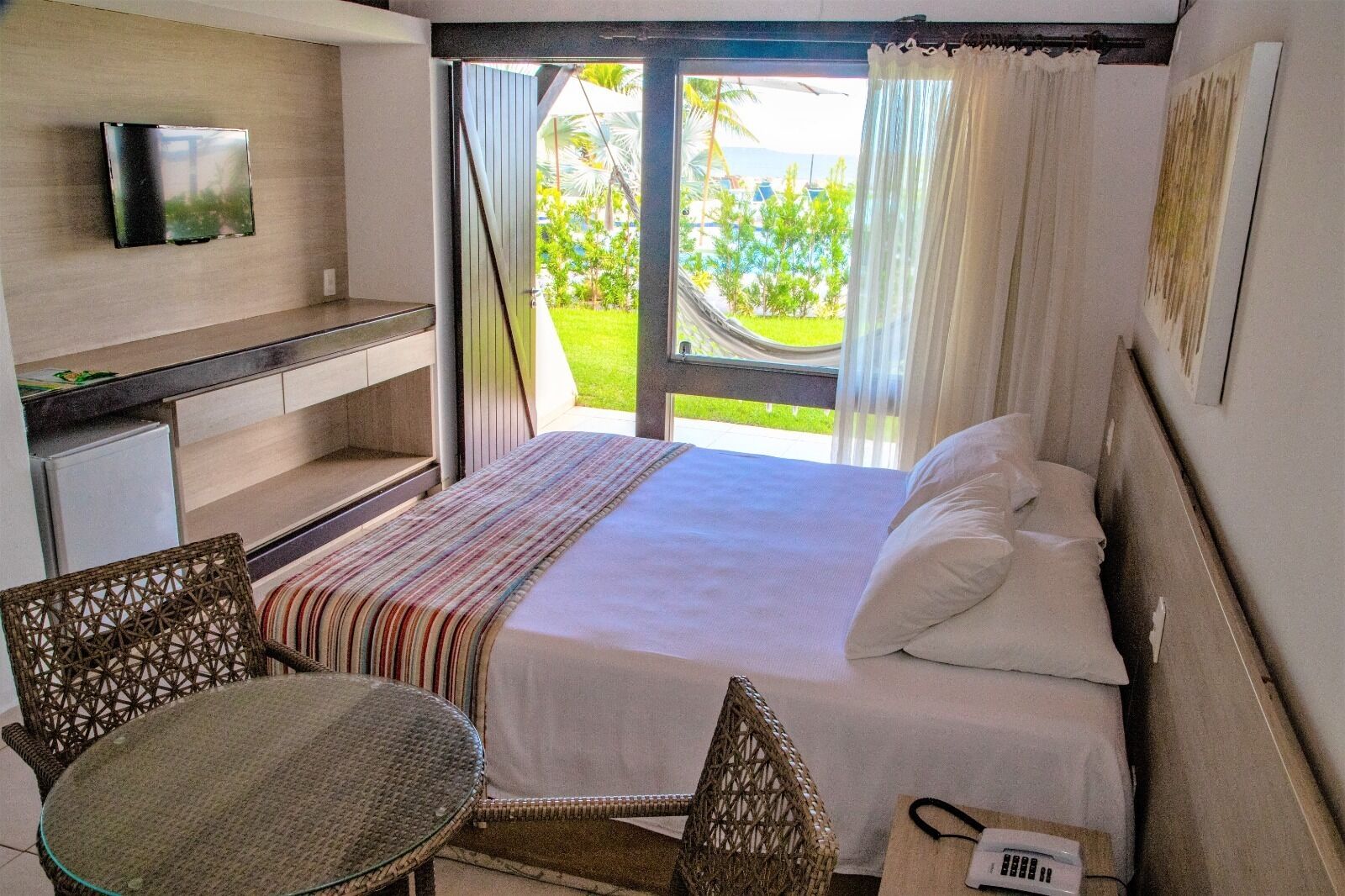 A hotel room with a bed, a small desk, a chair, and a table.