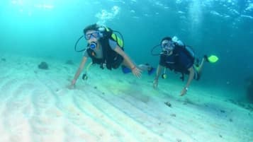 Dos buzos explorando bajo el agua, con aletas y tanques de oxígeno.