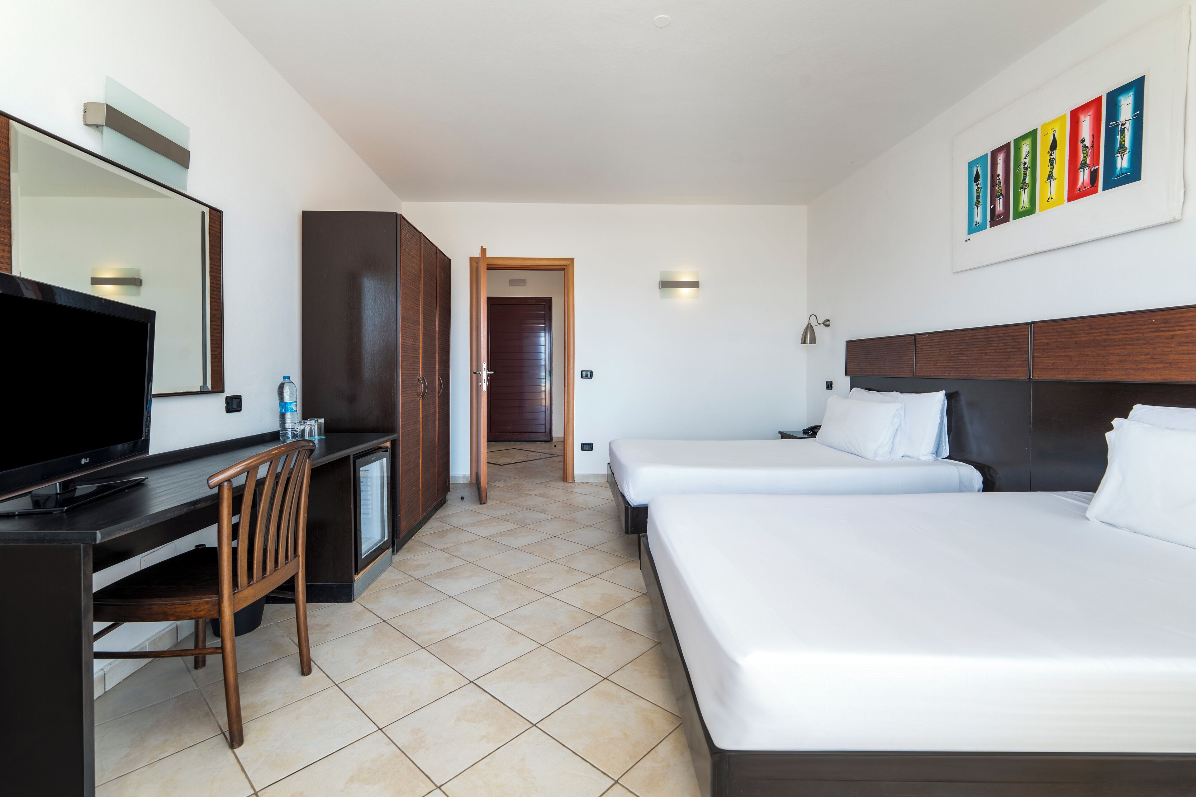 A hotel room with two beds, a TV, a desk, and a chair.