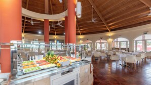 A buffet area with a variety of food options, a seating area with tables and chairs, and a high ceiling with wooden beams and ceiling fans. - Occidental Boa Vista Beach (Boa Vista)