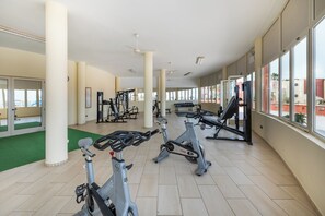Un gimnasio con cintas de correr, bicicletas estáticas y máquinas de pesas.