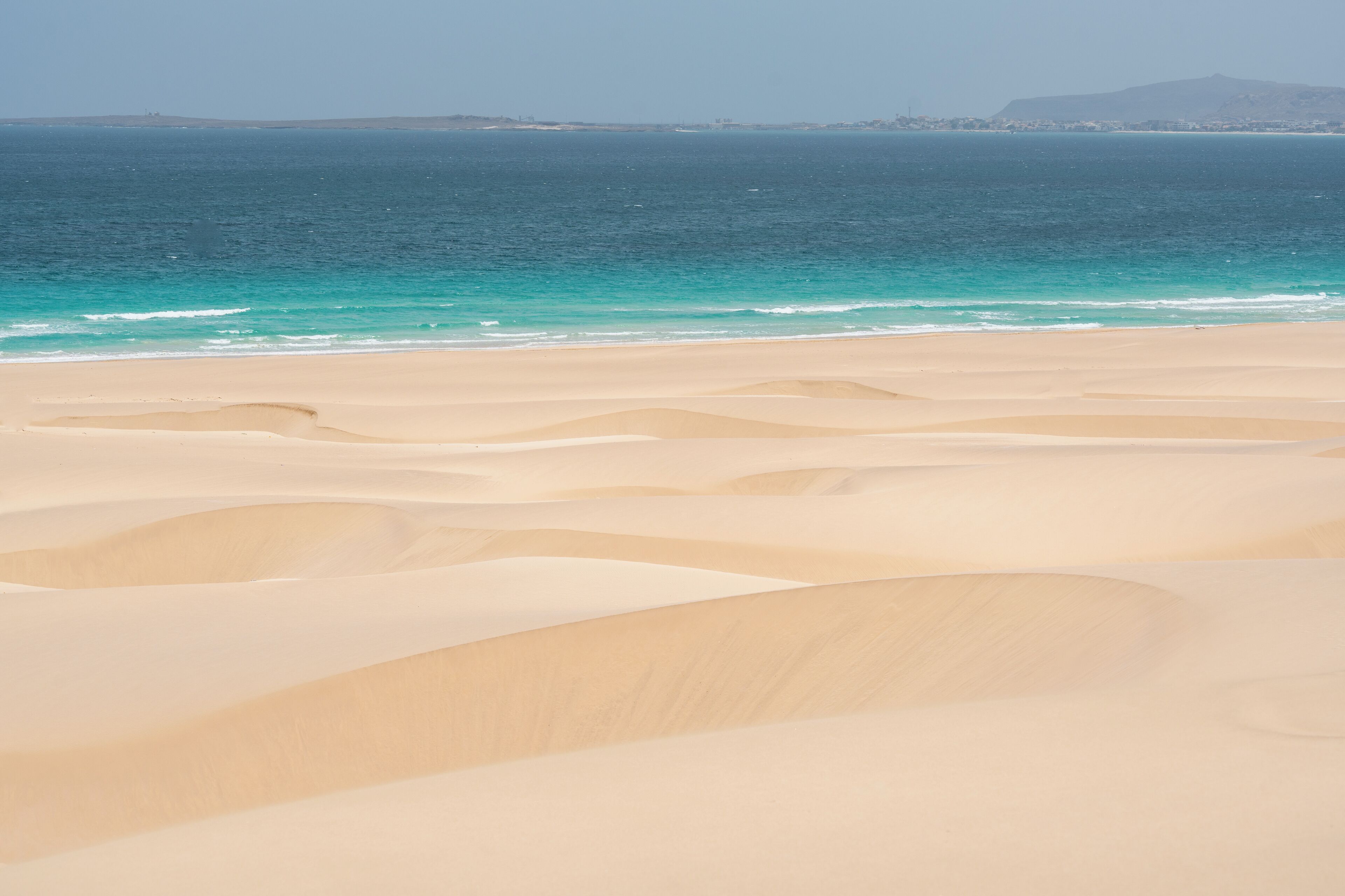Una playa con dunas de arena y una vista despejada del océano.