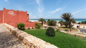 A coastal building with a red facade, a stone pathway, and a view of the beach and ocean. - Occidental Boa Vista Beach (Boa Vista)