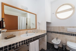 A bathroom with two sinks, a bidet, a toilet, a mirror, and a window. - Occidental Boa Vista Beach (Boa Vista)