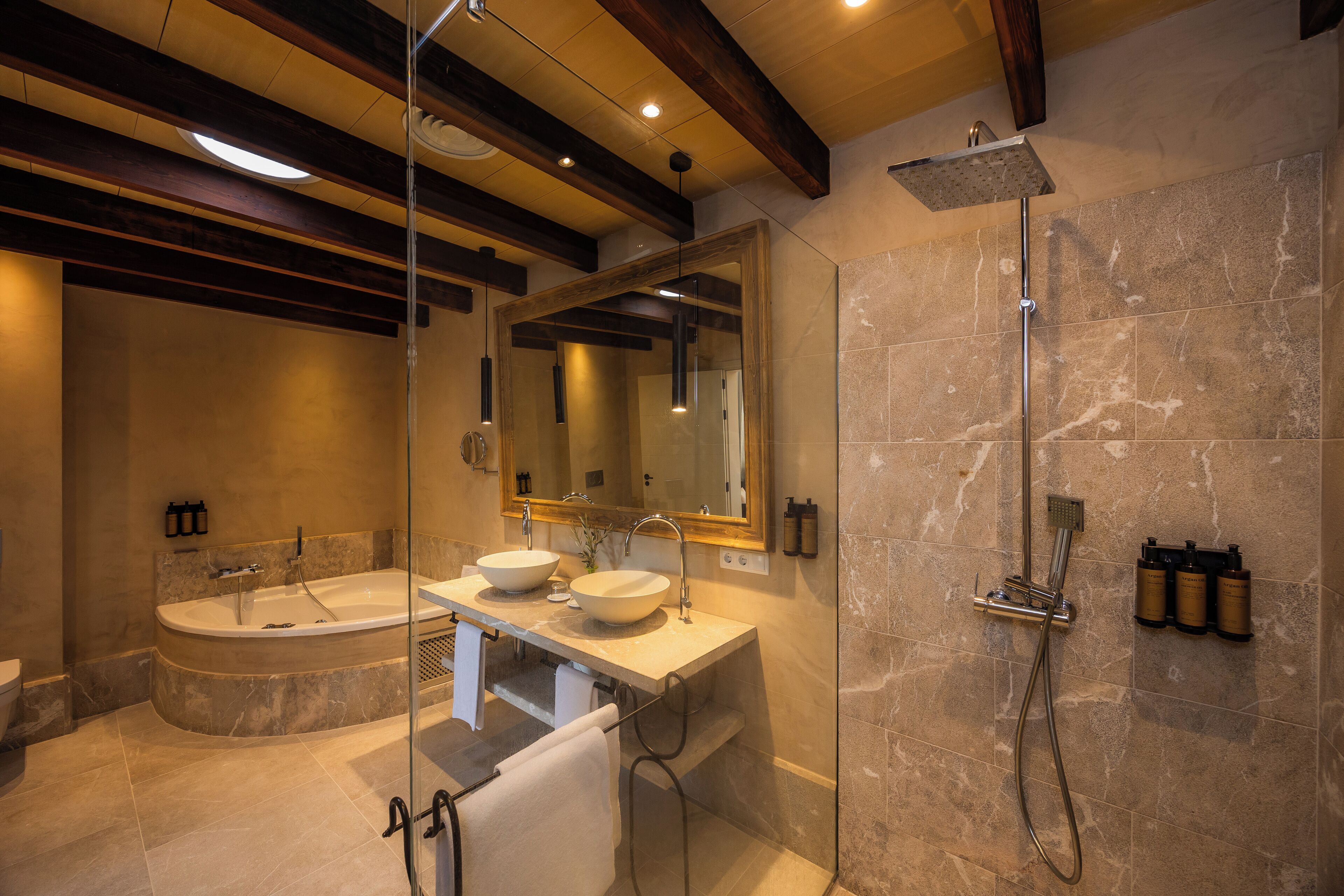 Un baño moderno con una bañera independiente, un tocador doble, ducha con cerramiento de vidrio y paredes de mármol.