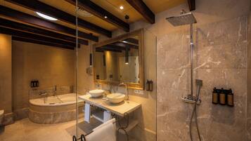 Un baño moderno con una bañera independiente, un tocador doble, ducha con cerramiento de vidrio y paredes de mármol.
