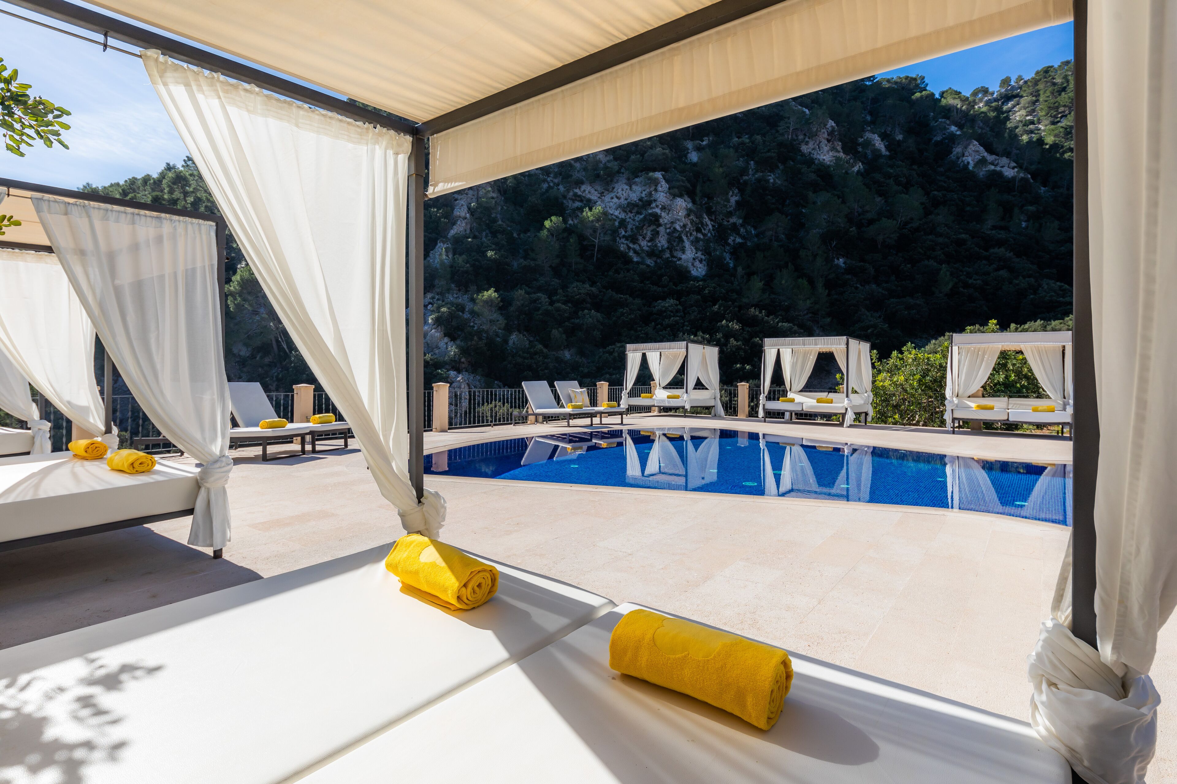 A poolside area with white canopies, yellow towels, and lounge chairs.