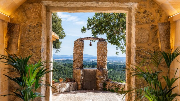 Un arco de piedra conduce a una vista de un paisaje montañoso.