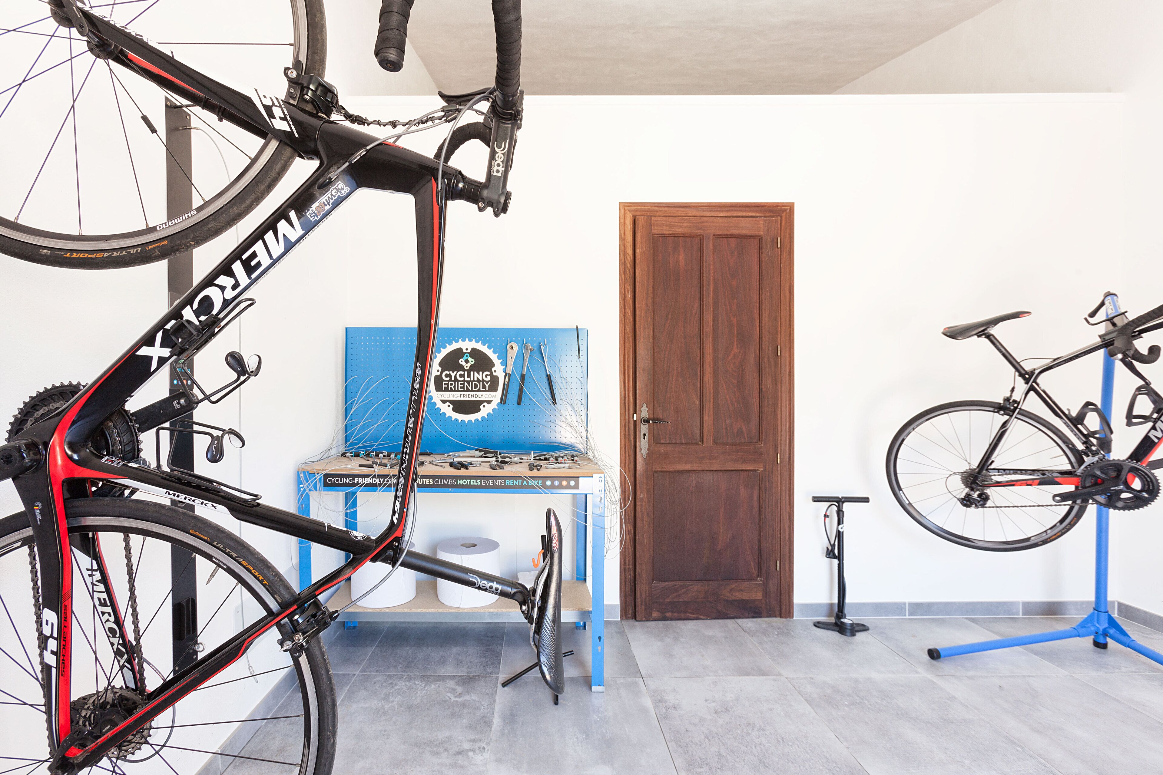 Una habitación con una bicicleta en un soporte, una puerta y una mesa azul con un cartel.
