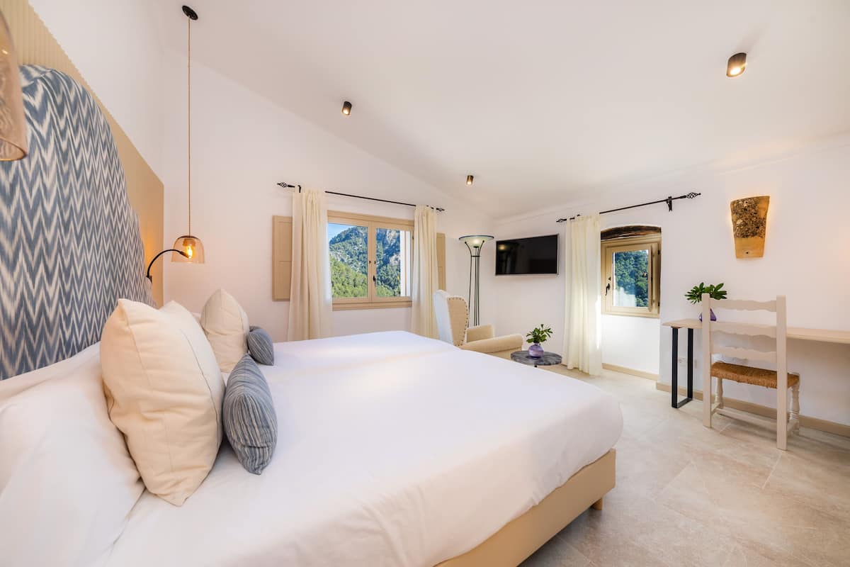 Ein modernes Schlafzimmer mit einem großen Bett, einem Schreibtisch, einem Stuhl und einem Fernseher.