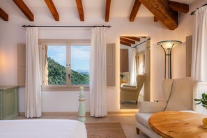 Un dormitorio con un ventanal grande, una cama, una silla y una lámpara.