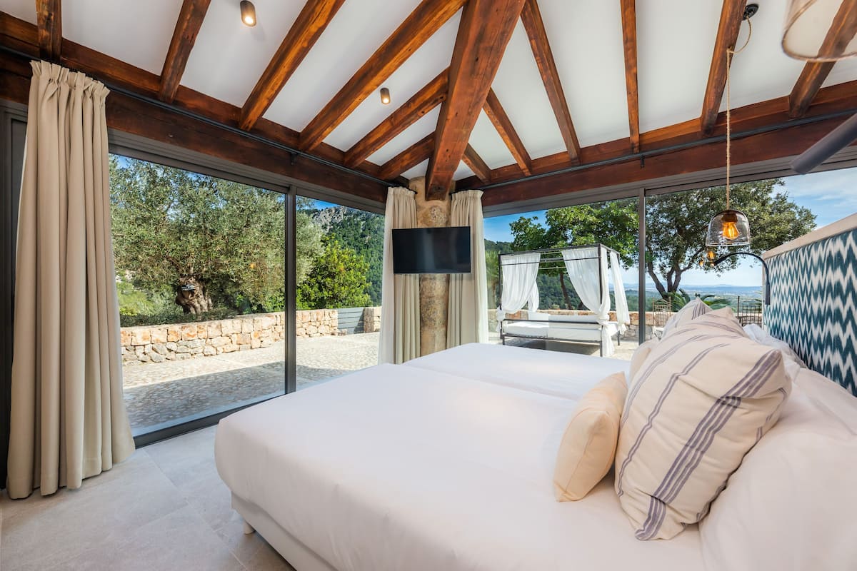 Ein geräumiges Schlafzimmer mit einem großen Bett, einem Fernseher und Blick ins Freie.