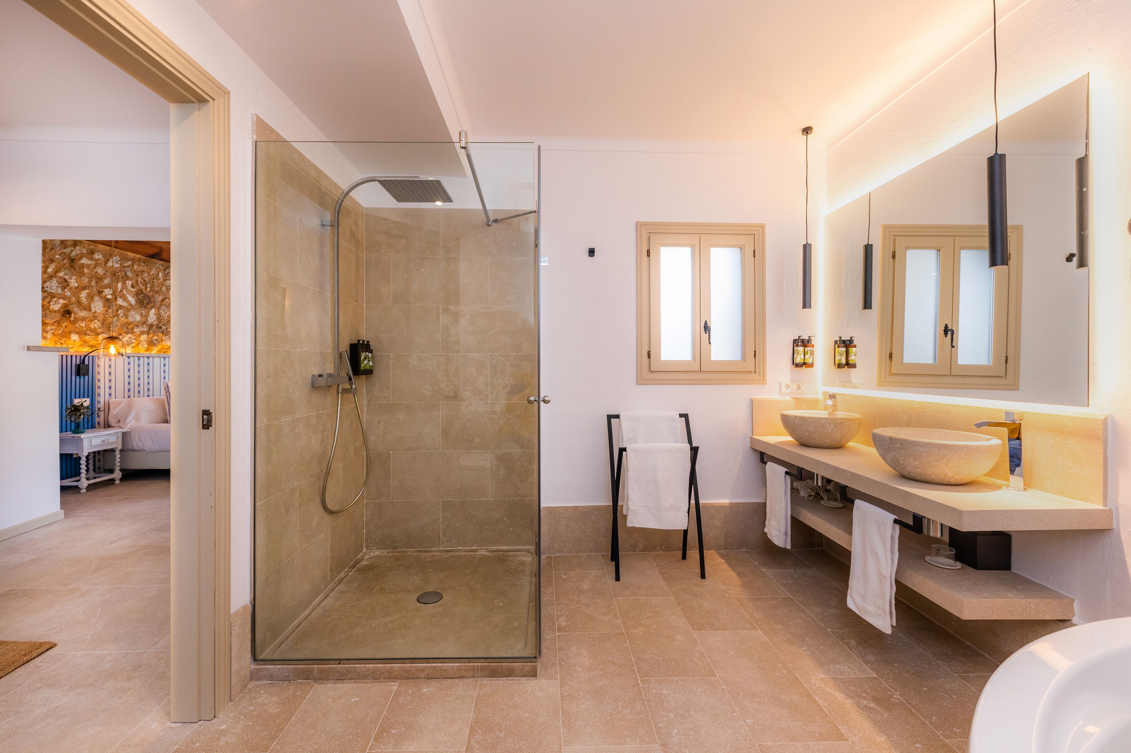 Un baño moderno con ducha de vidrio, tocador con lavabo y un espejo grande.