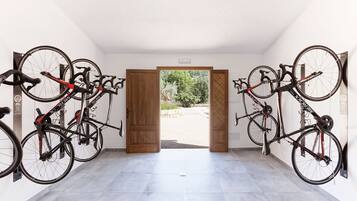 A room with bicycles mounted on the wall, a wooden door leading outside, and a tiled floor.