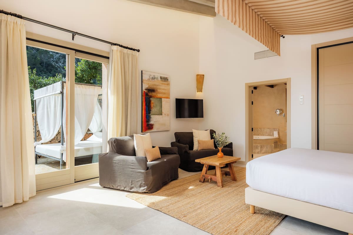 Ein modernes Schlafzimmer mit einem großen Bett, zwei Sofas, einem kleinen Tisch und einem Fernseher.