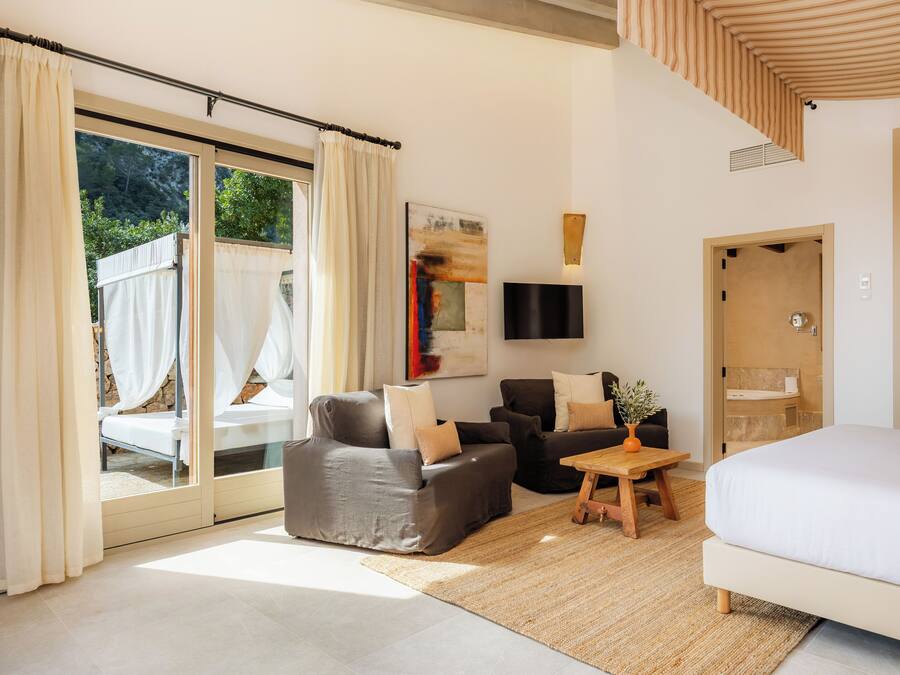 Ein modernes Schlafzimmer mit einem großen Bett, zwei Sofas, einem kleinen Tisch und einem Fernseher.