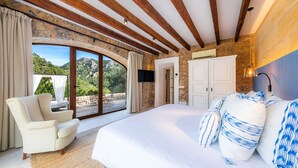 Un dormitorio con una cama grande, una silla, un televisor y vistas al exterior.