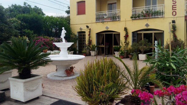 A courtyard with a fountain, potted plants, and a building labeled "ELISEO". - Hotel Eliseo (Giardini Naxos)
