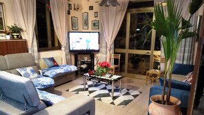 A living room with a sofa, a coffee table, a television, and a potted plant. - Hotel Eliseo (Giardini Naxos)