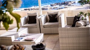 Eine Terrasse mit Korbmöbeln, einem Tisch mit Zeitschriften und Blick auf den Ozean.