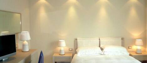 A hotel room with a bed, two bedside tables with lamps, a TV on a desk, and a chair.