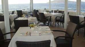 Ein Restaurant mit gedeckten Tischen und Meerblick.