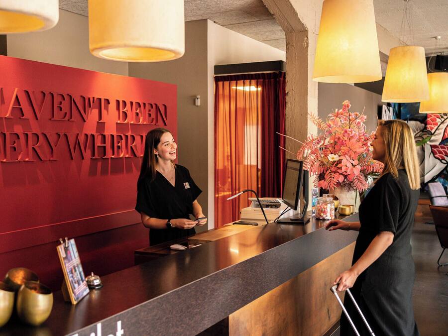 A reception desk with a red wall and a sign that reads "HAVE NOT BEEN VERY WHERE".