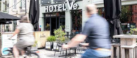 A hotel named HOTEL Ve with outdoor seating and potted plants.