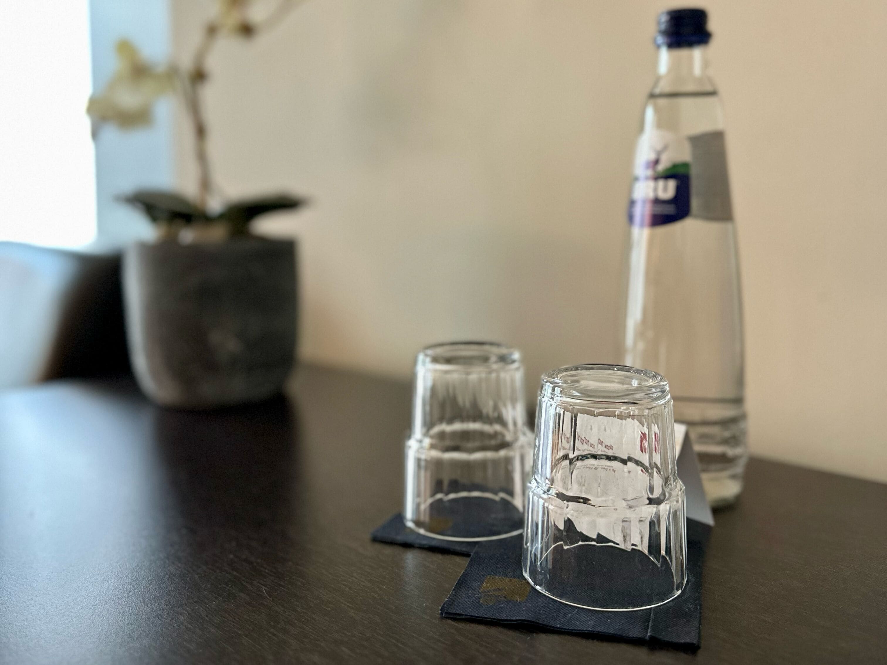 A table with two clear glasses and a water bottle.
