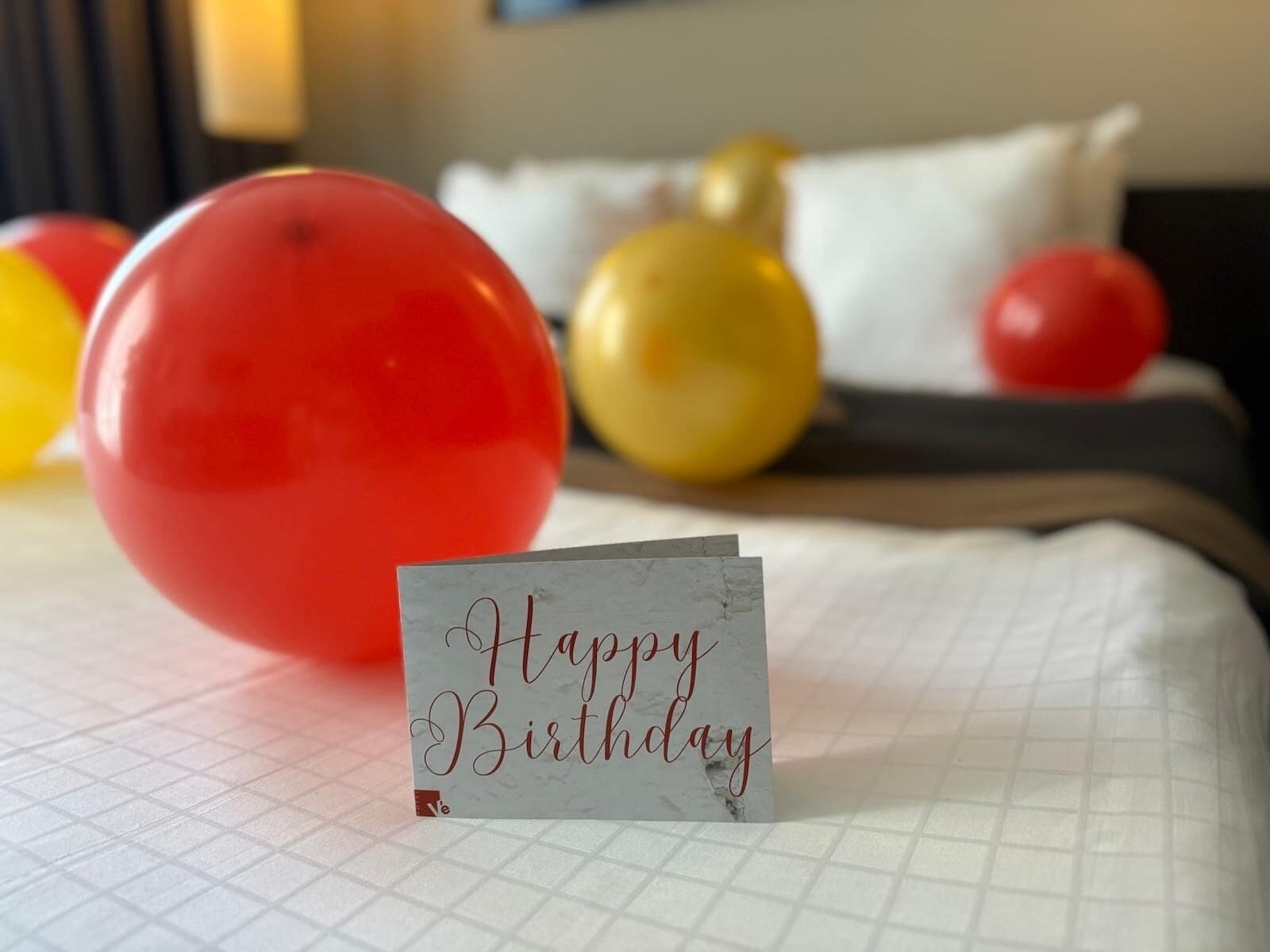 Un lit décoré d’une carte de vœux et de ballons.