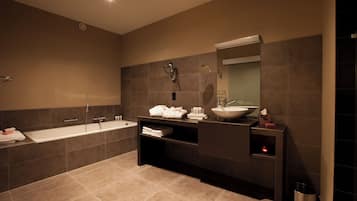 A modern bathroom with a large bathtub, a vanity with a sink, and a mirror.