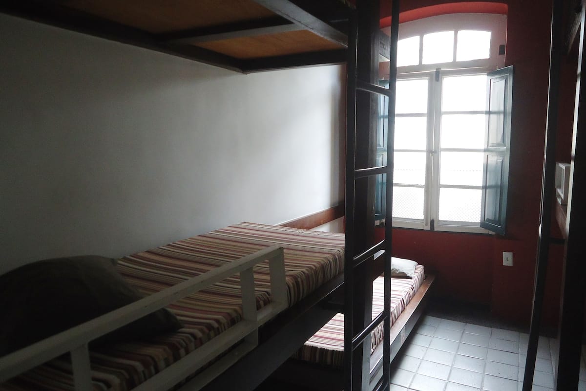 Ein Schlafsaalzimmer mit Etagenbetten, einem Fenster und einem Fliesenboden.