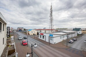 A hotel with a signboard, a road with cars, and a tall communication tower in the background.