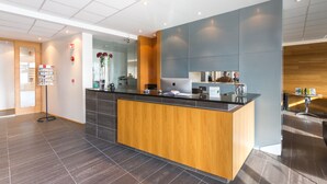 A modern reception area with a wooden reception desk, a large mirror, and a glass display stand.