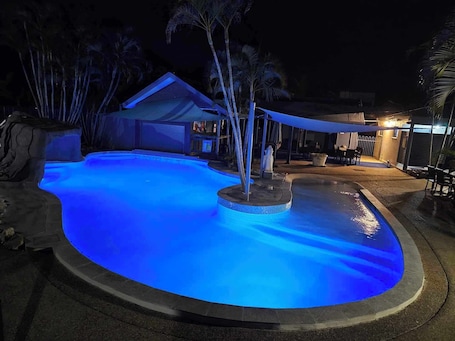Una piscina al aire libre, sombrillas, sillones reclinables de piscina
