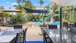 Un espace aménagé au bord de la piscine, avec des chaises longues, des parasols et une statue.