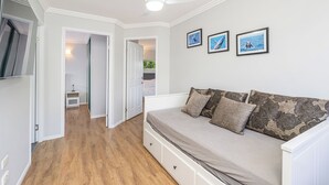 Une chambre à coucher avec un lit, un ventilateur de plafond et des tableaux encadrés accrochés au mur.