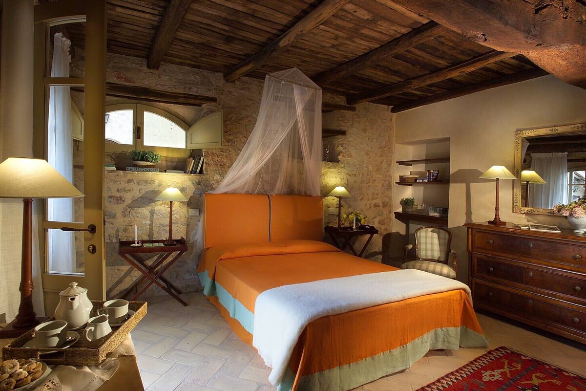 Ein gemütliches Schlafzimmer mit einem großen Bett, einer hölzernen Kommode und einer Steinwand.