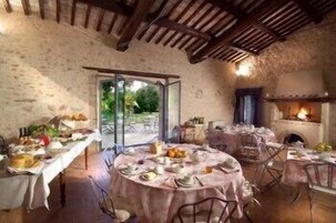 Un comedor rústico con mesas redondas cubiertas de manteles, una chimenea y vistas al exterior.