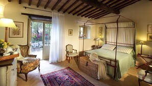 A traditional bedroom with a four-poster bed, a sitting chair, a side table, and a large window with curtains. - Borgo della Marmotta - Farm Home (Spoleto)