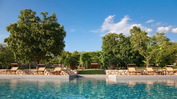 A clear swimming pool with lounge chairs and a stone wall. - Borgo della Marmotta - Farm Home (Spoleto)