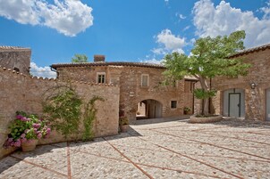 Un patio con muros de piedra, suelo de baldosas y plantas en macetas.