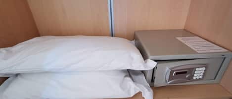 A hotel room with a bed, a small desk with a printer, and a wooden wardrobe.