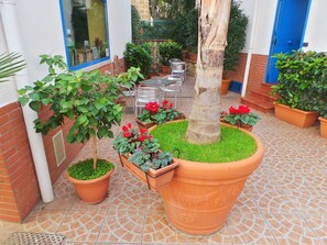 Une cour intérieure agrémentée de plantes en pot, d’un arbre et de mobilier d’extérieur.