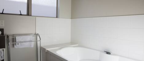 Un baño moderno con una bañera grande, un perchero para toallas y un ventanal.