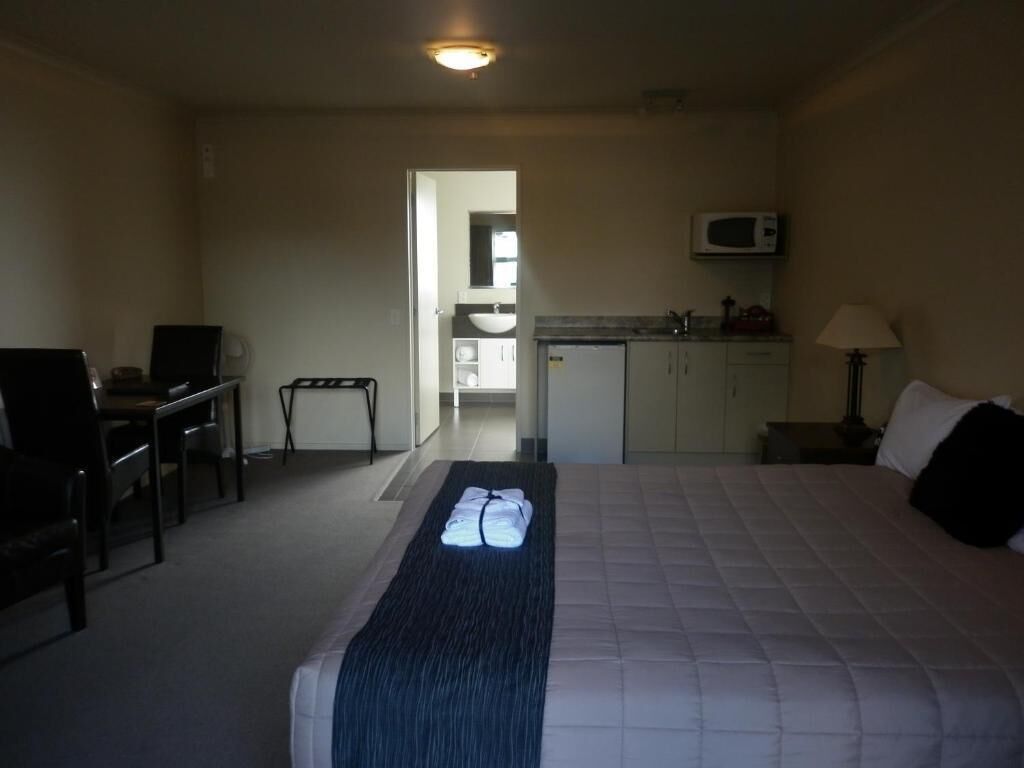 Une chambre d’hôtel équipée d’un lit, d’un bureau, d’une chaise, d’un four à micro-ondes et d’une kitchenette.