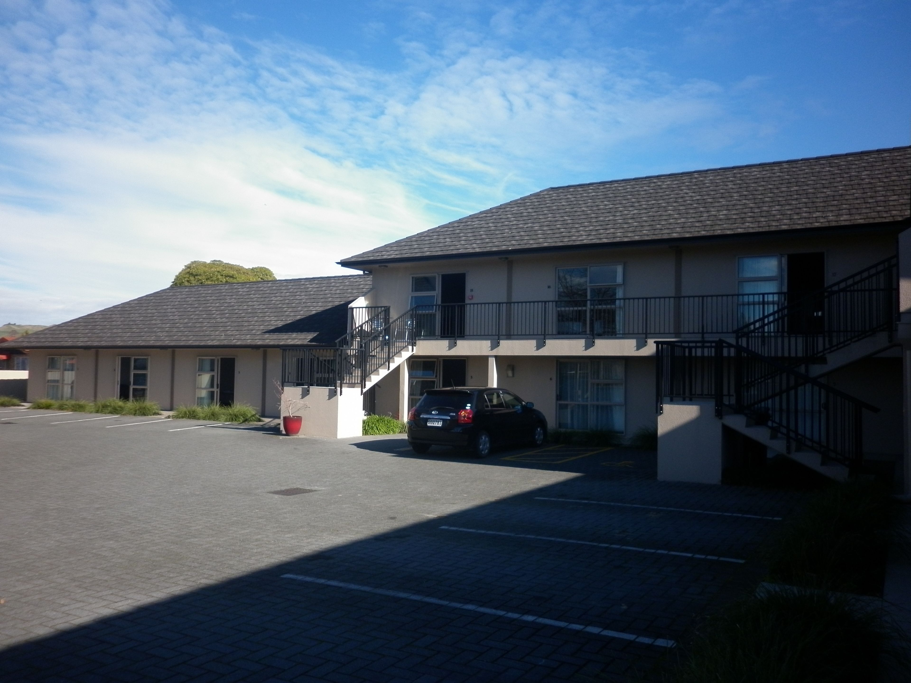 Un bâtiment à deux étages avec un parking et une voiture garée devant.
